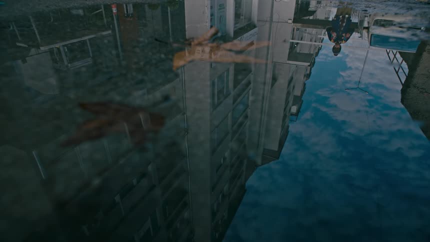 Closeup on the ground with a bet of water reflecting urban buildings and a little boy
