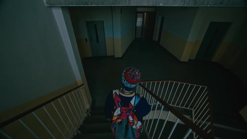 A boy in a beanie is walking down the stairs
