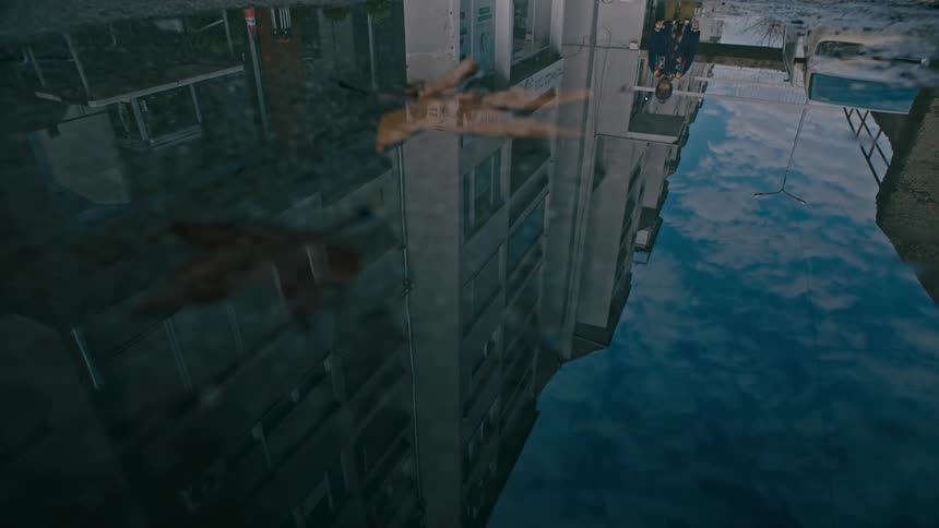 Closeup of the puddle of water on the ground reflecting buildings and a child