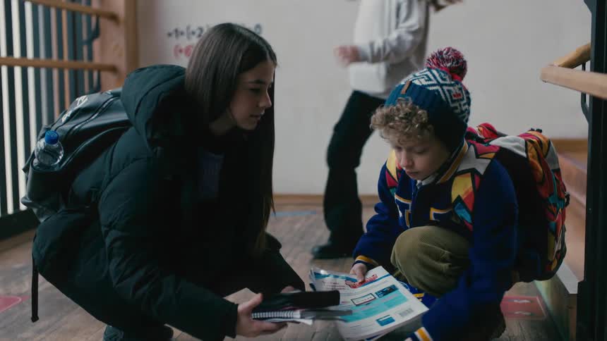 A boy helps a girl pick up books