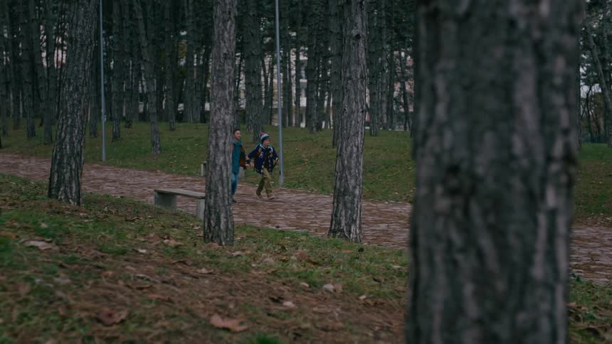 Two schoolboys meet on the road and run downhill in the public park