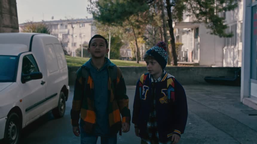 Two children talking while walking out of a alley during the day