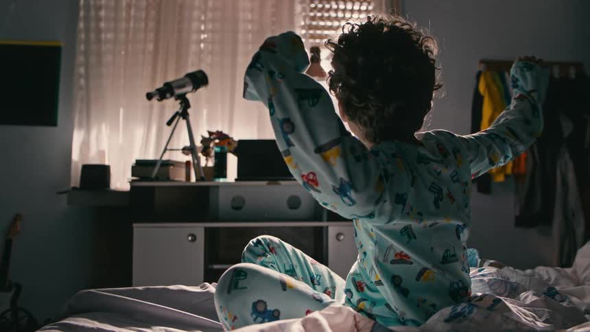 A tired young boy wakes up and gets out of bed