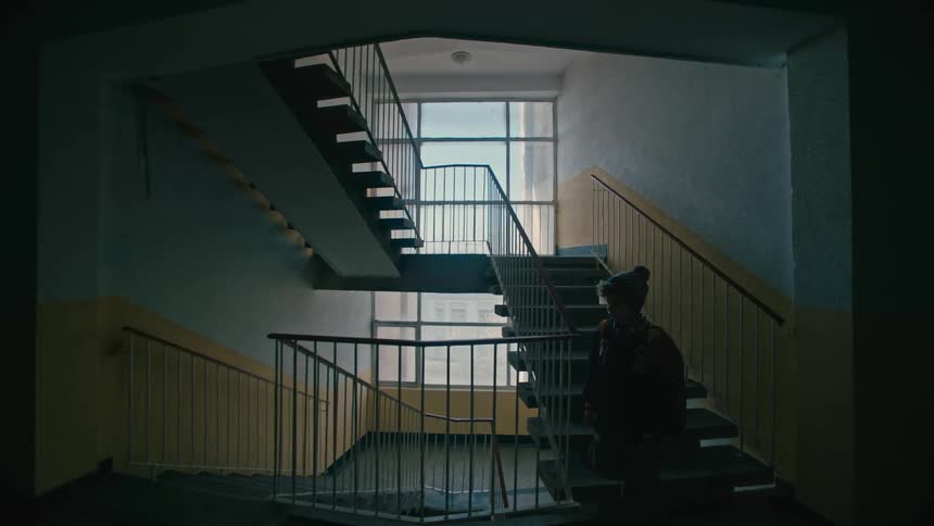 A young boy descends a set of stairs while indoors at school