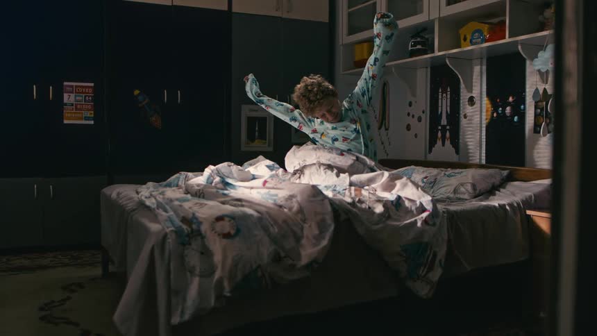 A young boy in pajamas wakes up and gets out of bed