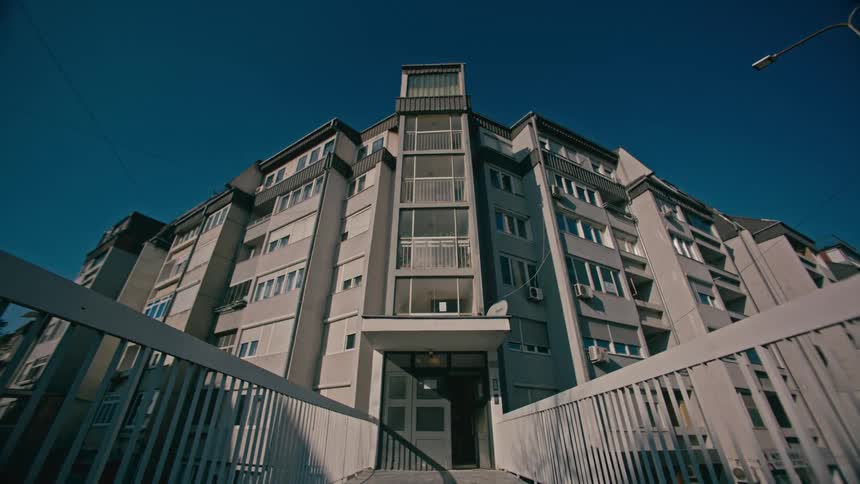 A large concrete apartment building stands tall under a blue sky