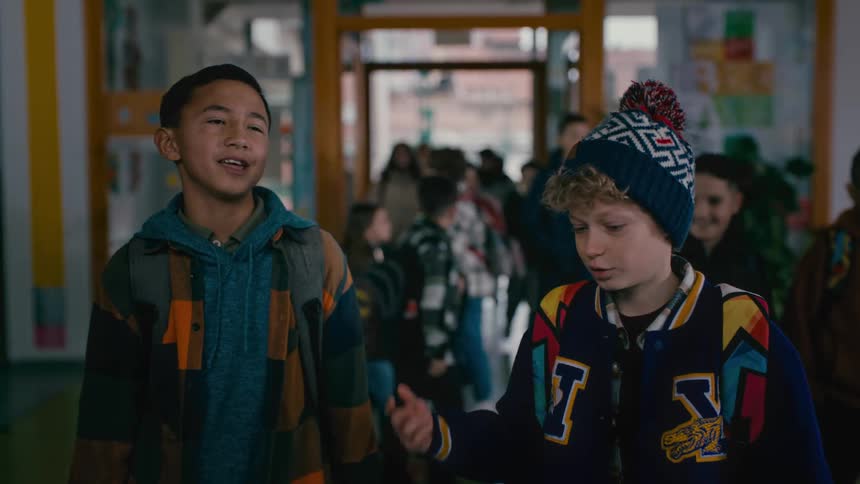 Two friends saying goodbye touching hands in the school hallway