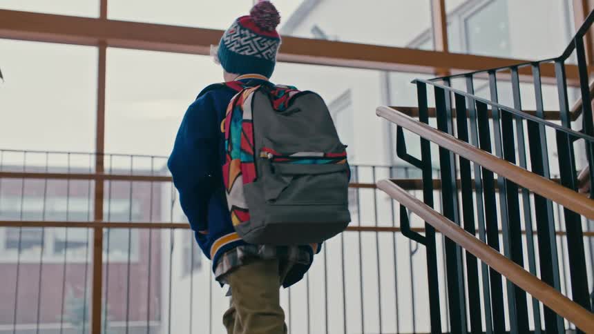 A student helps another student pick up her notebooks on a school staircase