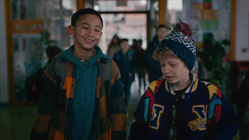 Two friends saying goodbye in the school hallway with other children around