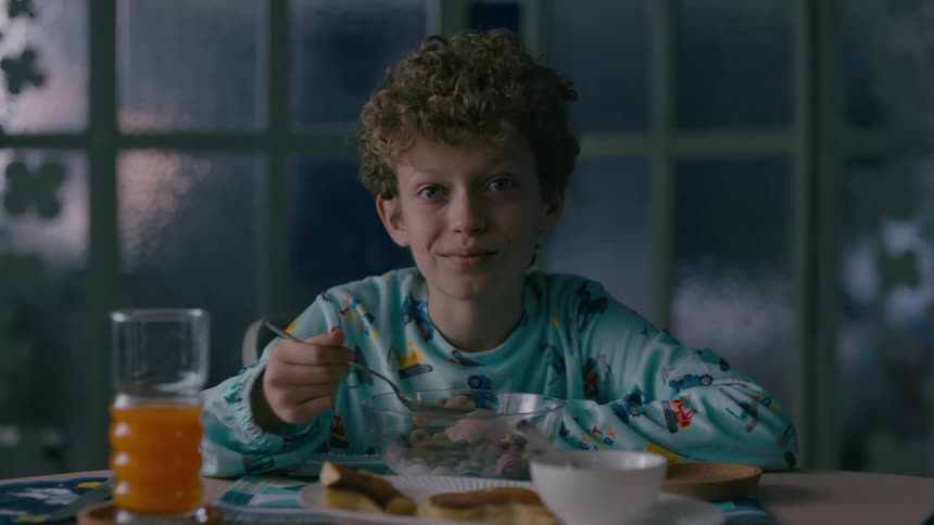 Smiling little boy eating cereal at the table