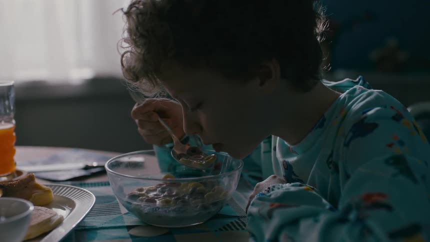 Little boy sitting at the table eating cereal