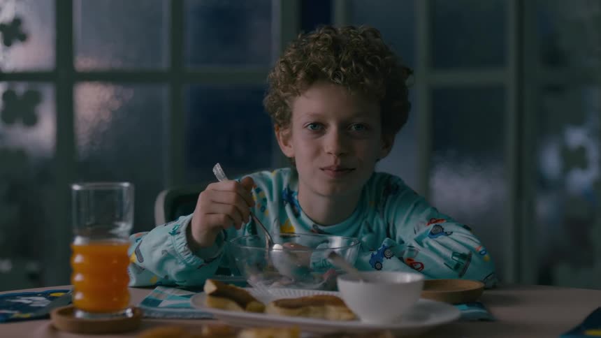 Smiling little boy eating cereal at the table