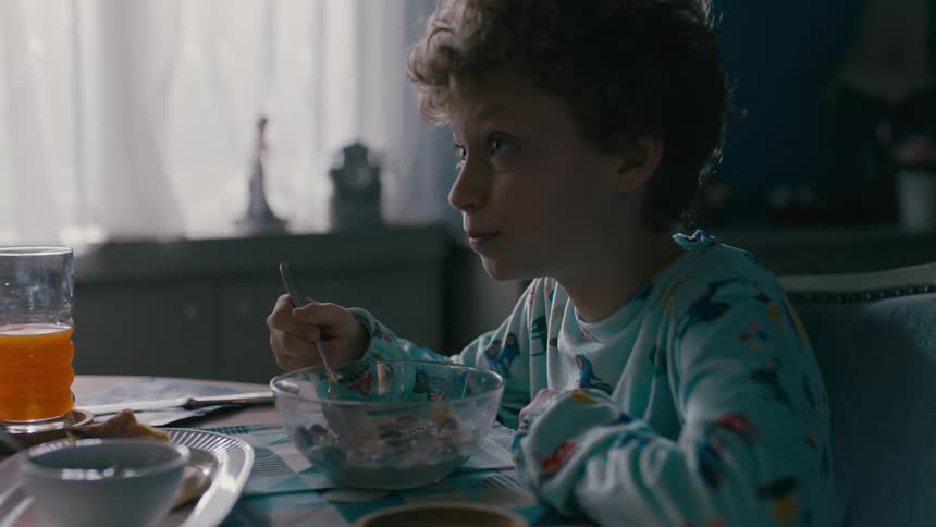 Boy wearing pajamas eating cereal for breakfast at home