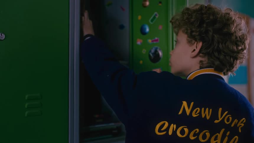 A male child putting books from his school locker inside his backpack