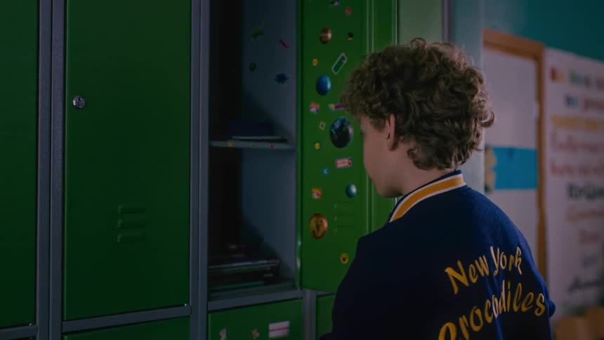 A boy getting his school supplies from a locker at school