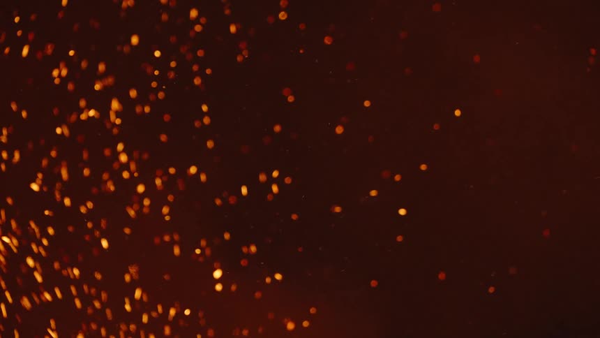 Closeup on shrapnel of burnt fire rising in a dark environment