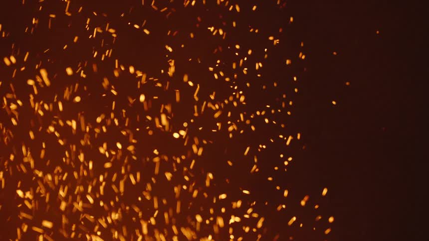 A fire generates lots of sparks and burning coal type substances