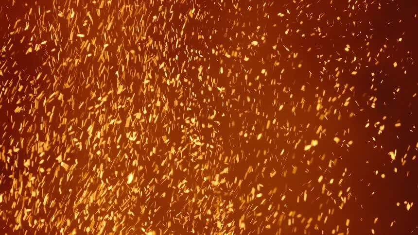 Glowing embers move as they rise in the smoke of a fire