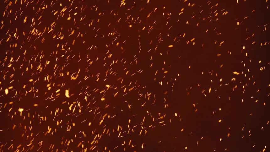 Glowing embers move as they float in the darkness