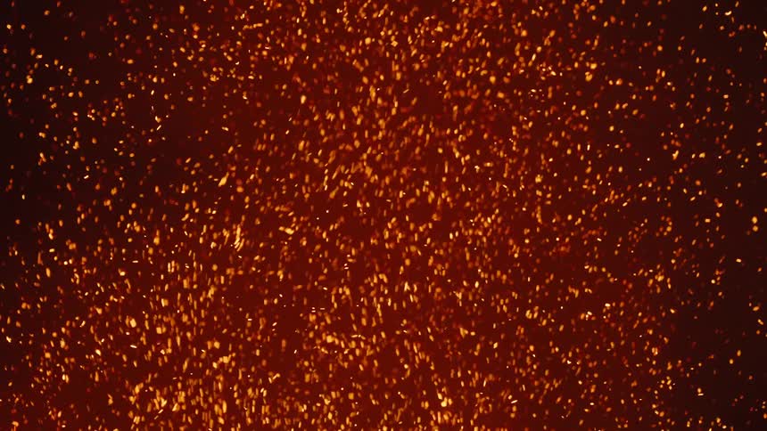 Glowing embers rise in the smoke of a fire