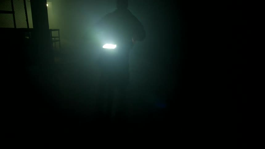 A silhouette of a person riding a motorcycle with headlights on in a dark environment