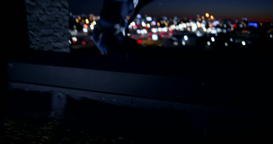 Closeup of a persons feet jumping over a building at night