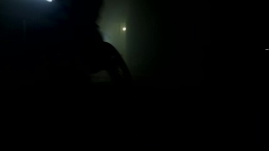 The silhouette of two motorcyclists driving in a dark interior with only the motorcycle headlights on