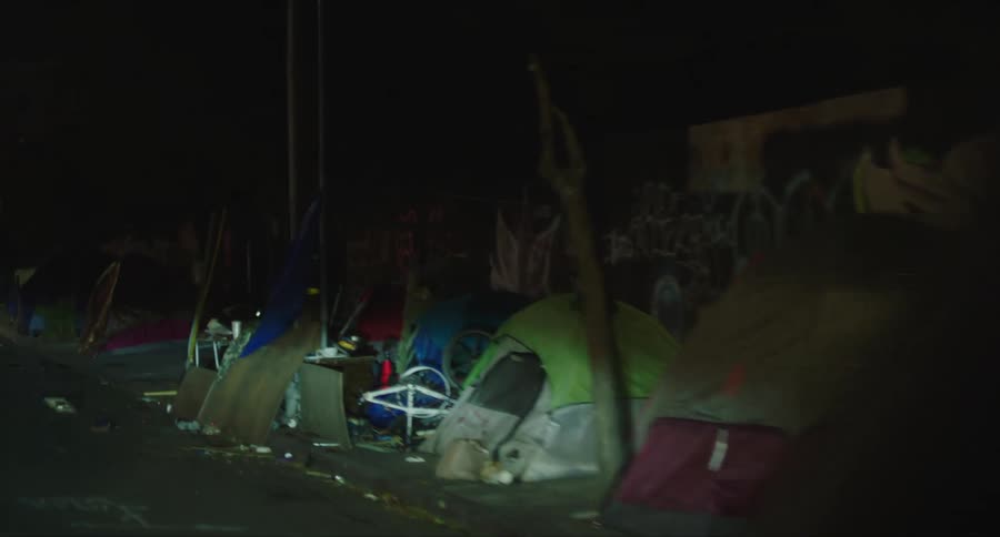 Street of a night city with graffiti on the walls and tents set up