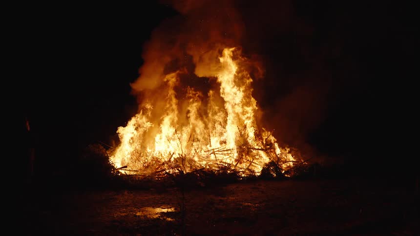 Smoke rises from large fire burning outside at night