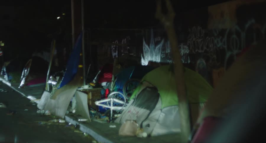 Alley of a street at night with tents of homeless people