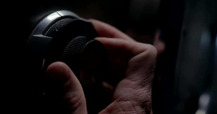 Closeup of a mans hand spinning a code for a safe