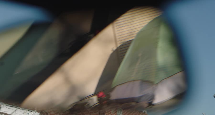 View from inside the car of tents made from houses in the middle of an abandoned street