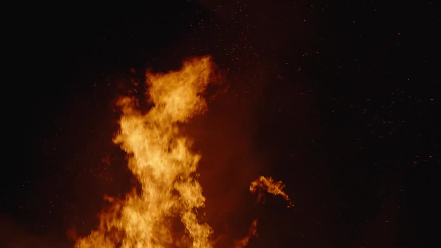 A fire burns brightly and releases smoke into the air above itself