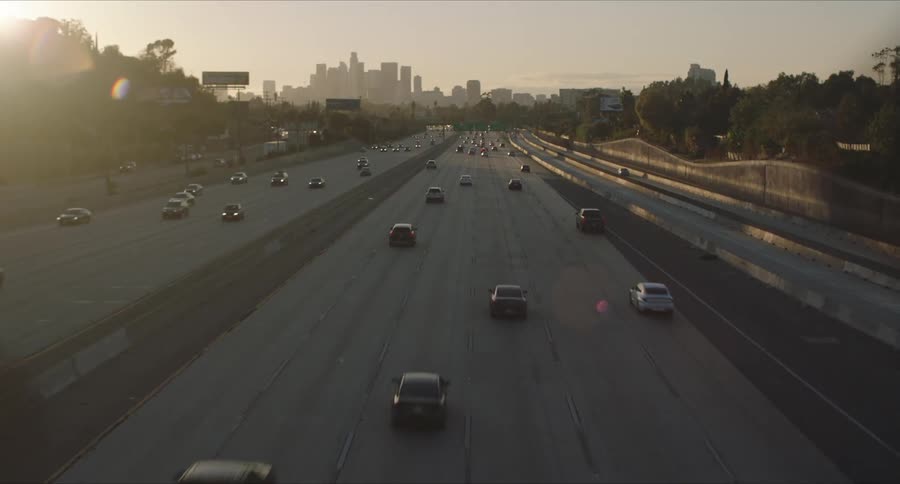 A large freeway with traffic and downtown Los Angeles in the background