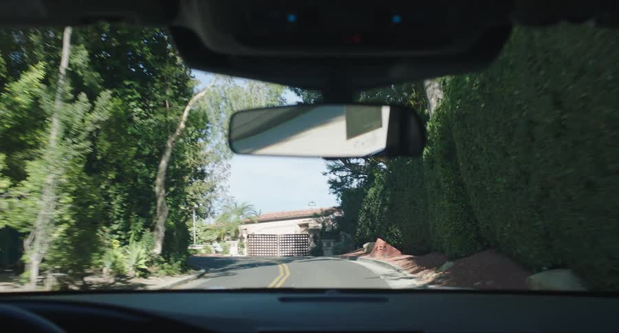 View from inside a car moving through streets and a residential neighborhood