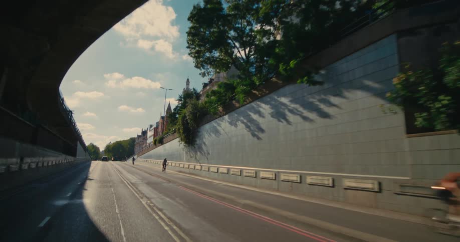 An asphalt street with some cyclists passing by and there is a tunnel