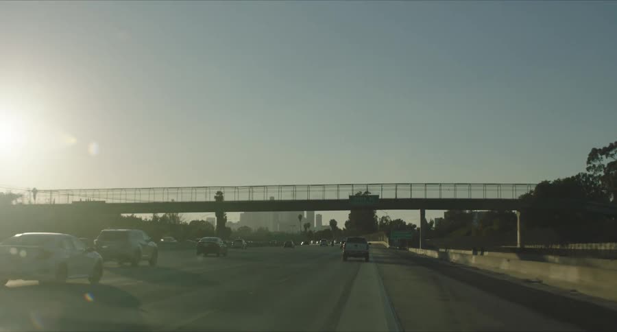 Traffic flows along highway toward city skyline on a sunny day