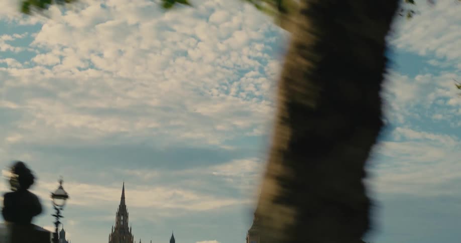 People move through park across river from the palace of westminster on a cloudy day