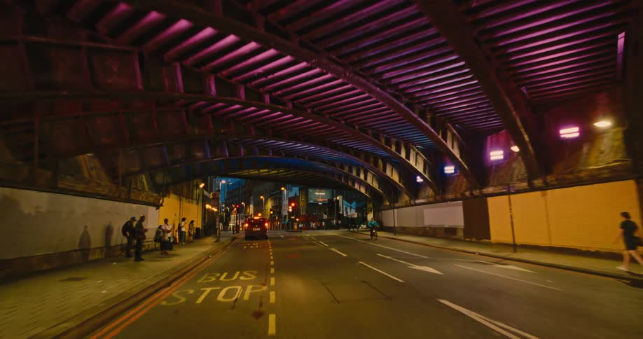 Vehicle moving on a city road and people walking on the sidewalk at night