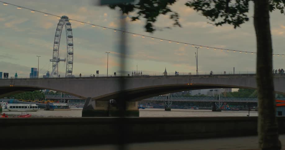 A ferris wheel and people crossing a bridge seen from a moving vehicle