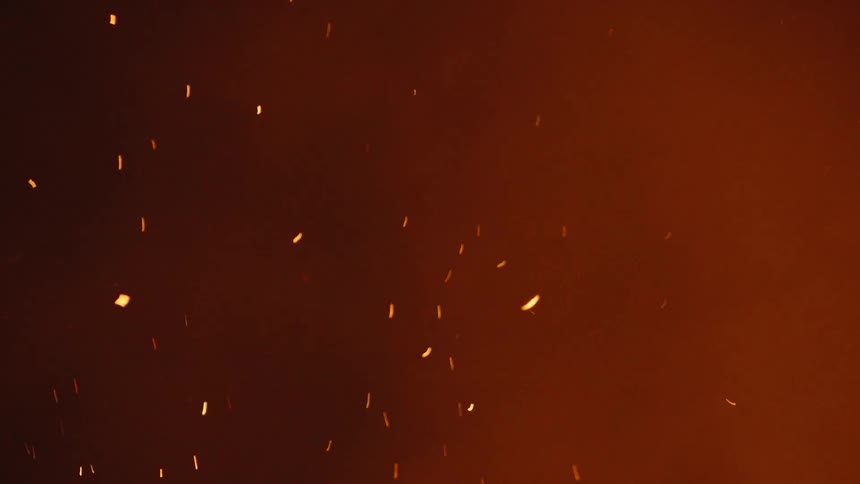 Embers and smoke from fire rising at night