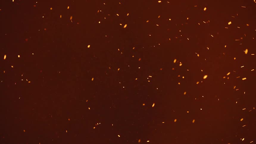 Many particles of orange sparks on a solid background