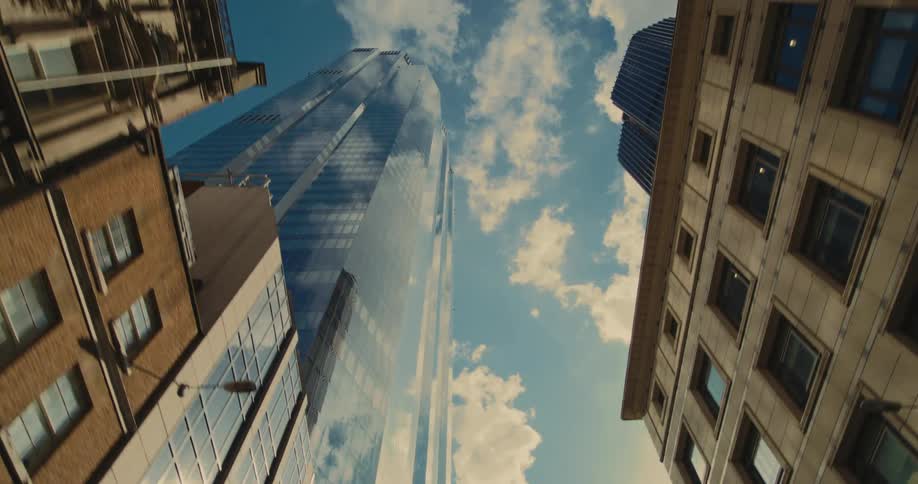 Upward view of residential and commercial buildings with skyscrapers on a blue sky day with clouds