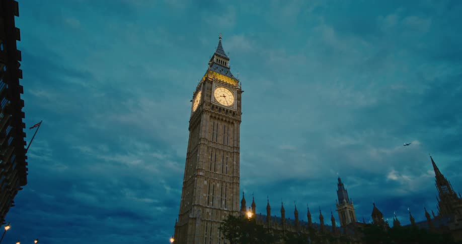 London buses drive past Big Ben at dusk
