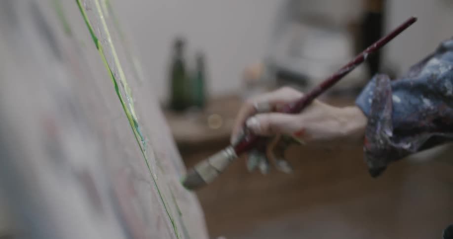A woman paints on a large canvas