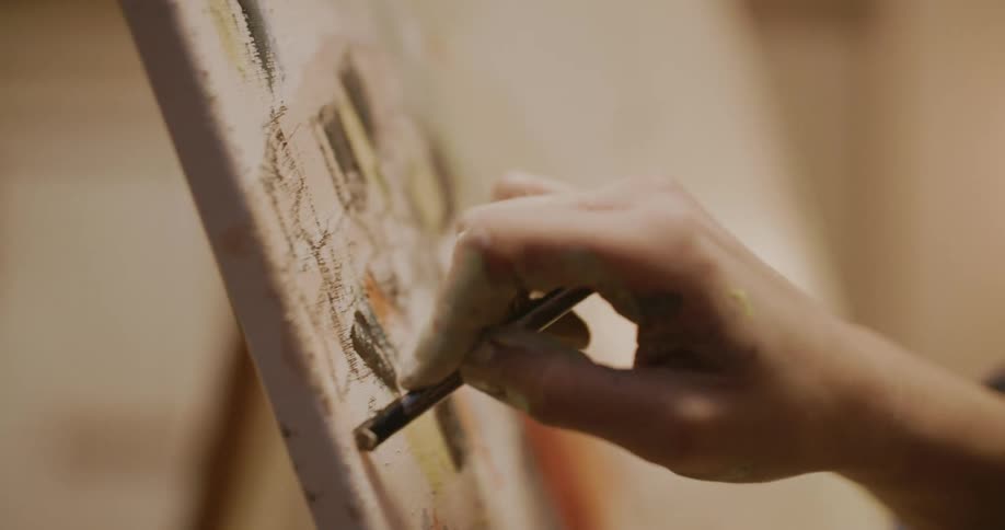 A white woman draws with chalk on a canvas