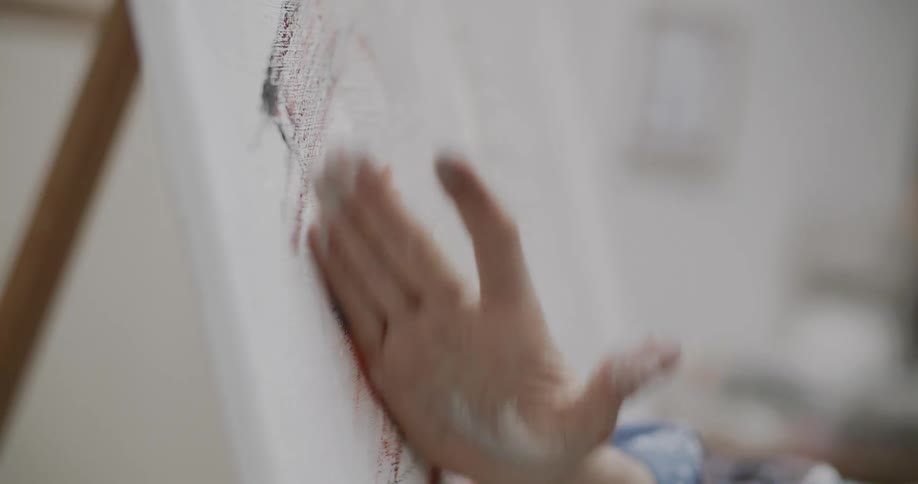 Closeup of a womans hand spreading paint on a whiteboard