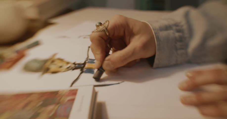 A woman using a box of professional crayons to sketch on paper