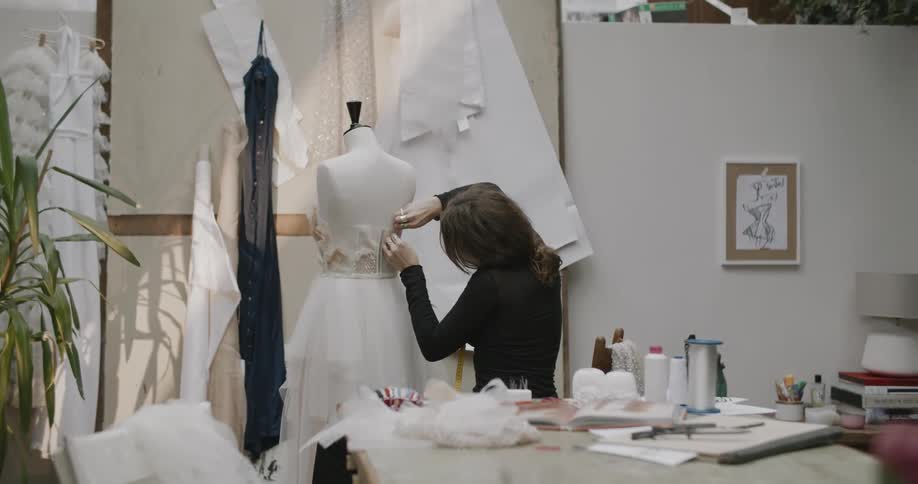Woman adjusting the back of a wedding dress on the mannequin