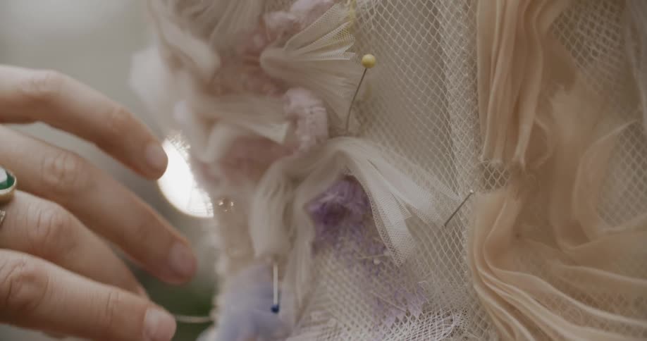 Closeup of a womans hands sewing the back of a dress